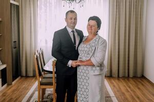 A man and a woman are standing in a room with a dining table in the background photo