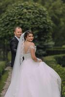 A bride and groom are posing for a picture in front of a hedge photo