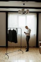 A man is standing in front of a clothes rack photo