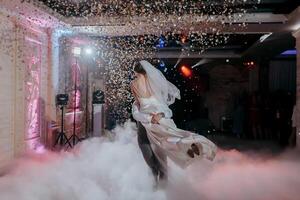 A bride and groom are dancing in the air with confetti falling around them photo