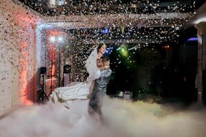 A bride and groom are dancing in the air with confetti falling around them photo