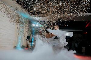 A bride and groom are dancing in the air with confetti falling around them photo