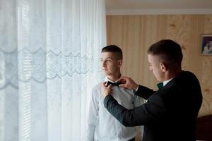 Two men are getting ready for a formal event photo