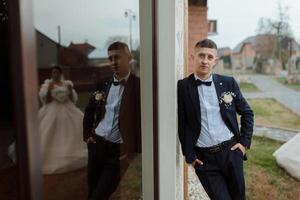 A man in a suit and tie stands in front of a mirror photo