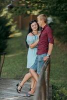A man and a woman are standing on a bridge, smiling at each other photo