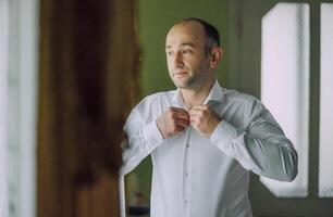 A man is getting dressed in front of a window photo