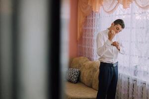 A man is getting dressed in front of a window photo