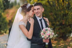 A bride and groom are hugging each other in a park photo