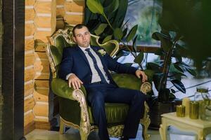 A man in a suit is sitting in a green chair photo