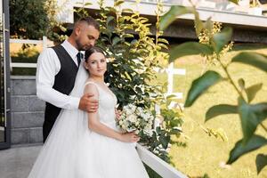A bride and groom are posing for a picture in front of a fence photo