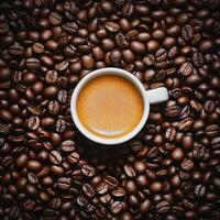 A steaming cup of coffee placed on a bed of roasted coffee beans photo