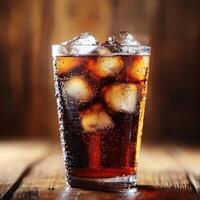 A refreshing glass of soda filled with ice cubes, sitting on a wooden surface photo