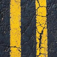 A close-up view of an asphalt road texture with a bold yellow stripe running along one side photo