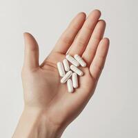 handful of white pills being held in an open hand, with the pills resting naturally in the palm photo