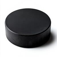 A close-up image of a classic hockey puck, made of rubber, isolated on a pure white background. The puck has a matte black surface photo
