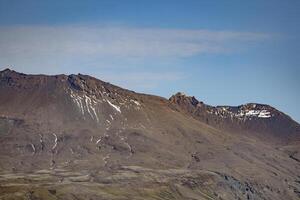 Iceland views. A mountain range with snow on the top and a clear blue sky photo