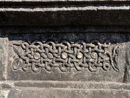 A detailed closeup of a snake carving on Halebidu Temples wall in Karnataka showcases Hoysala artistry, with precise scales, coiled form, and intricate light and shadow details. photo