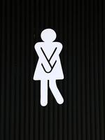 Creative Female Restroom Sign with Urgency Pose on Dark Background, Perfect for Bathroom Signage Concepts photo