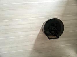 Modern Wall-Mounted Round Tissue Dispenser on Light Wooden Background, Perfect for Bathroom Design Concepts photo