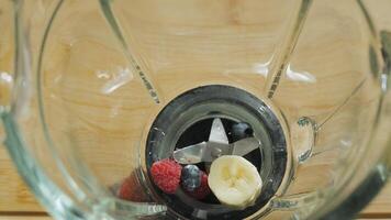 Adding raspberries, blueberries and bananas to a blender to make a smoothie. The smoothie ingredients are ready to be blended. video