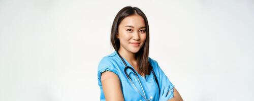 Healthcare and medical concept. Vaccinated female asian doctor showing arm with patch after covid-19 vaccine, smiling pleased, white background photo