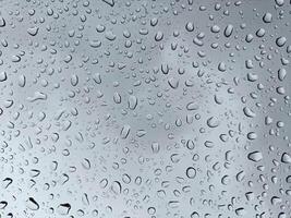 Raindrops on the window glass with a dark cloud background photo