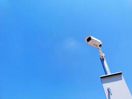 White surveillance camera or security CCTV or close circuit television with installed on steel pole outdoor and monitor and record for property protection with white sky background and copy space. photo
