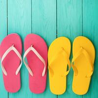 Three pairs of colorful flip flops on a wooden background photo