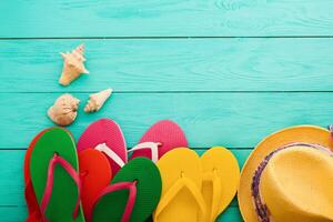 Colorful flip flops and hats on a blue wooden table photo