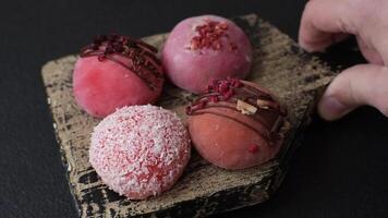 Delicious colorful asian mochi sweets with rice dough shell and fruit filling on dark concrete background video