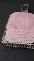 Boiled ham cut into square slices with sorrel and spices on a dark concrete background video