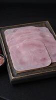 Boiled ham cut into square slices with sorrel and spices on a dark concrete background video