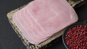 Boiled ham cut into square slices with sorrel and spices on a dark concrete background video