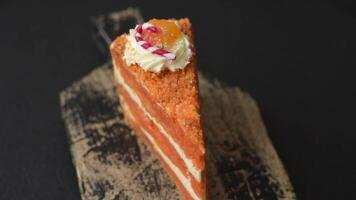 Piece of sweet layer cake with pumpkin or citrus flavor with cream on a dark textured background video