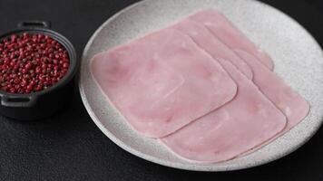 Boiled ham cut into square slices with sorrel and spices on a dark concrete background video