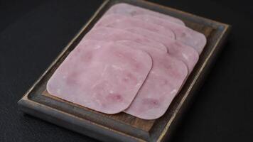 Boiled ham cut into square slices with sorrel and spices on a dark concrete background video