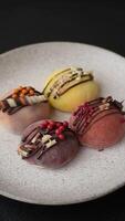 Delicious colorful asian mochi sweets with rice dough shell and fruit filling on dark concrete background video