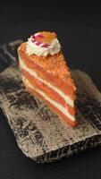 Piece of sweet layer cake with pumpkin or citrus flavor with cream on a dark textured background video