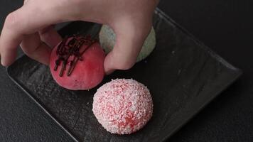 Delicious colorful asian mochi sweets with rice dough shell and fruit filling on dark concrete background video