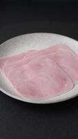 Boiled ham cut into square slices with sorrel and spices on a dark concrete background video