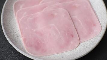Boiled ham cut into square slices with sorrel and spices on a dark concrete background video