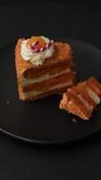 Piece of sweet layer cake with pumpkin or citrus flavor with cream on a dark textured background video