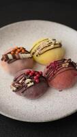 Delicious colorful asian mochi sweets with rice dough shell and fruit filling on dark concrete background video