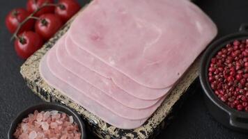 Boiled ham cut into square slices with sorrel and spices on a dark concrete background video