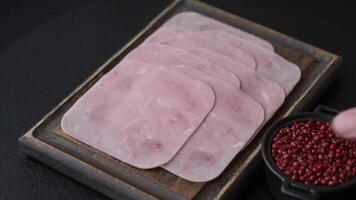 Boiled ham cut into square slices with sorrel and spices on a dark concrete background video