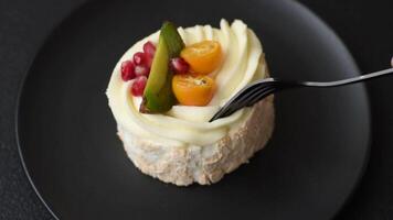 Piece of sweet meringue with citrus, kiwi and pomegranate seeds on a dark concrete background video