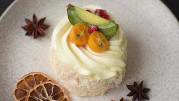 Piece of sweet meringue with citrus, kiwi and pomegranate seeds on a dark concrete background video