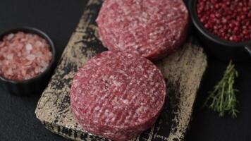 Fresh raw ground beef burger patty with salt and spices on textured concrete background video