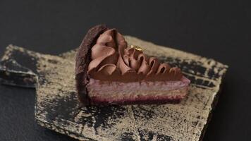A piece of sweet cheesecake with mascarpone cheese, strawberry flavor, covered with chocolate on a dark concrete background video