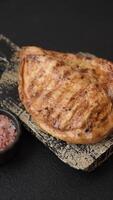 Grilled chicken fillet with salt, spices and herbs on a dark concrete background video